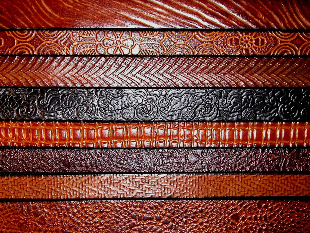 Eight tooled belts laid side by side, reds and browns