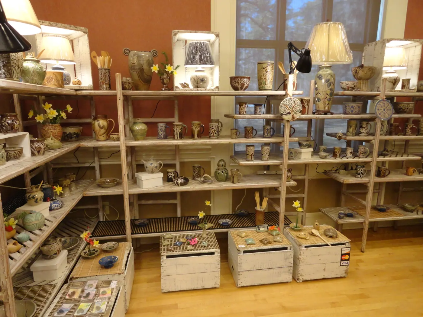 Wooden shelves of pottery and lit lamps
