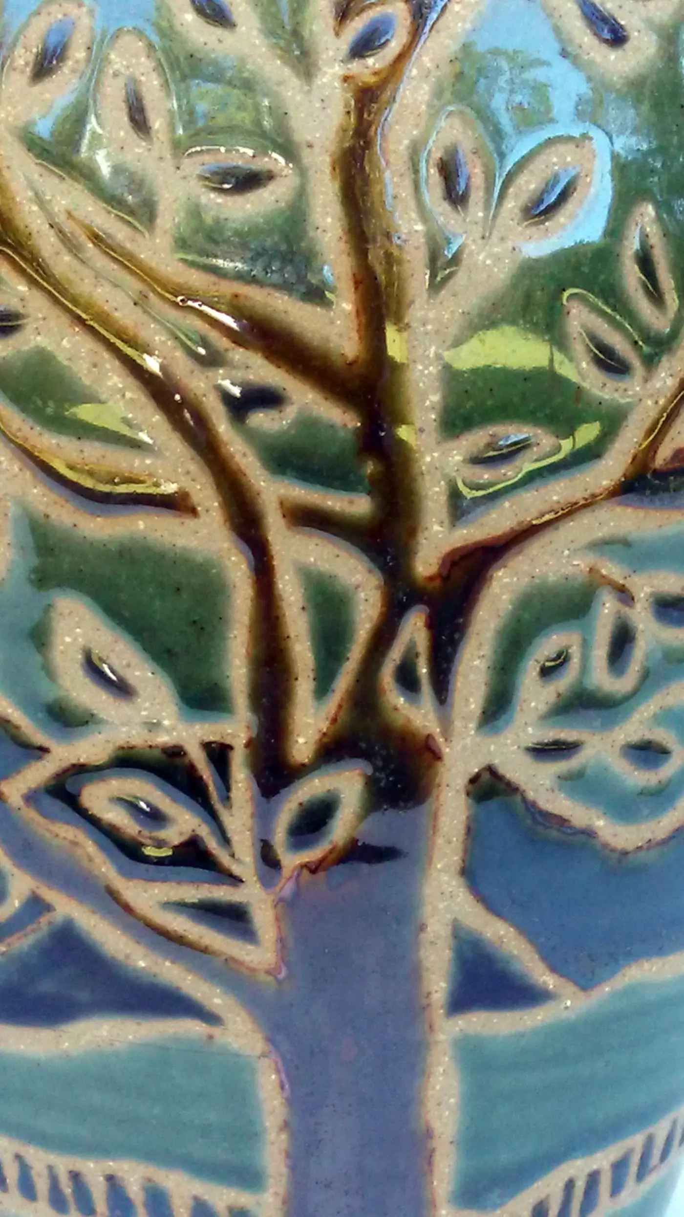 Detail of a carved tree on a green and blue glazed vase