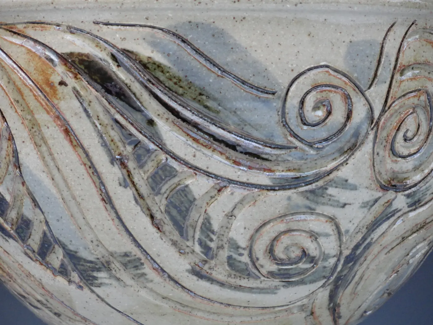 Close detail of carved swirls in a glazed stoneware bowl